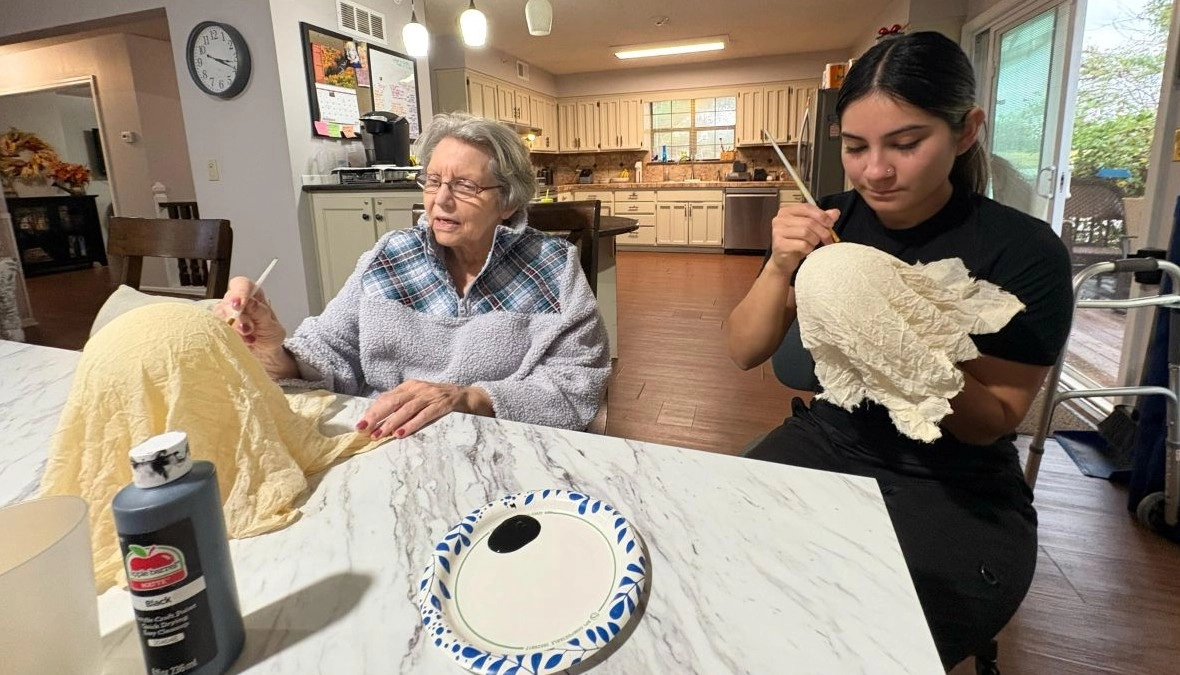 Nurse and elderly resident painting together at a senior care community