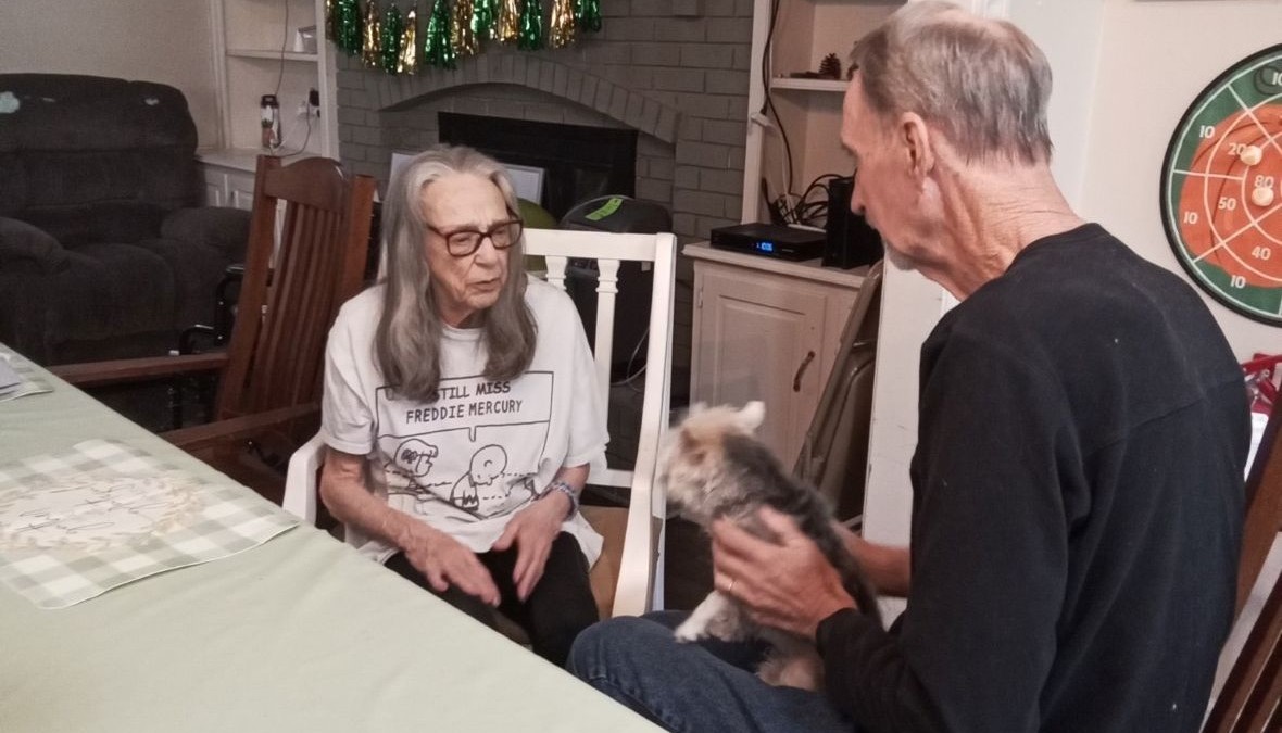 Nurse holding a dog and talking to a senior citizen
