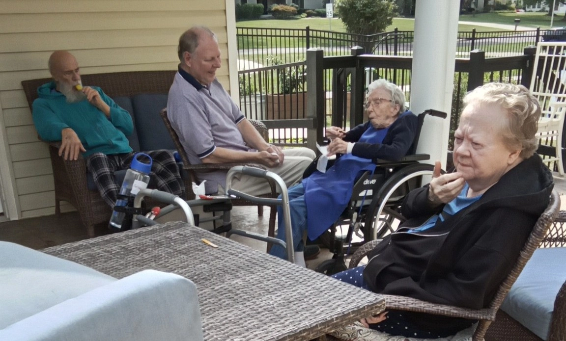 Senior residents relaxing together on an outdoor patio at a senior care community