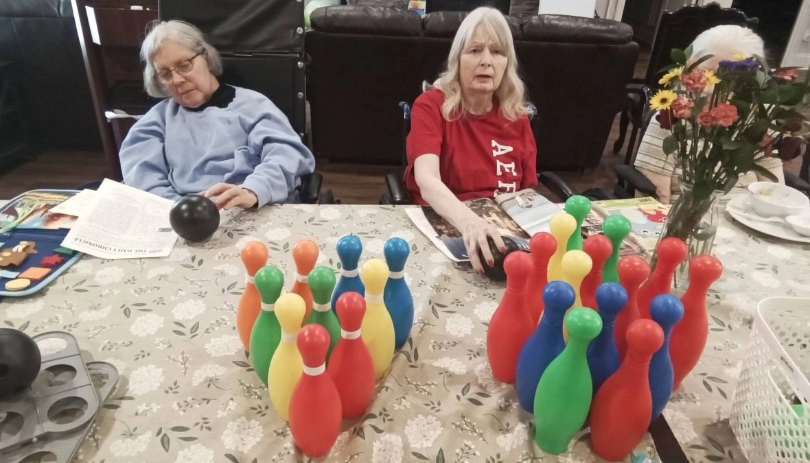 Two seniors playing table bowling